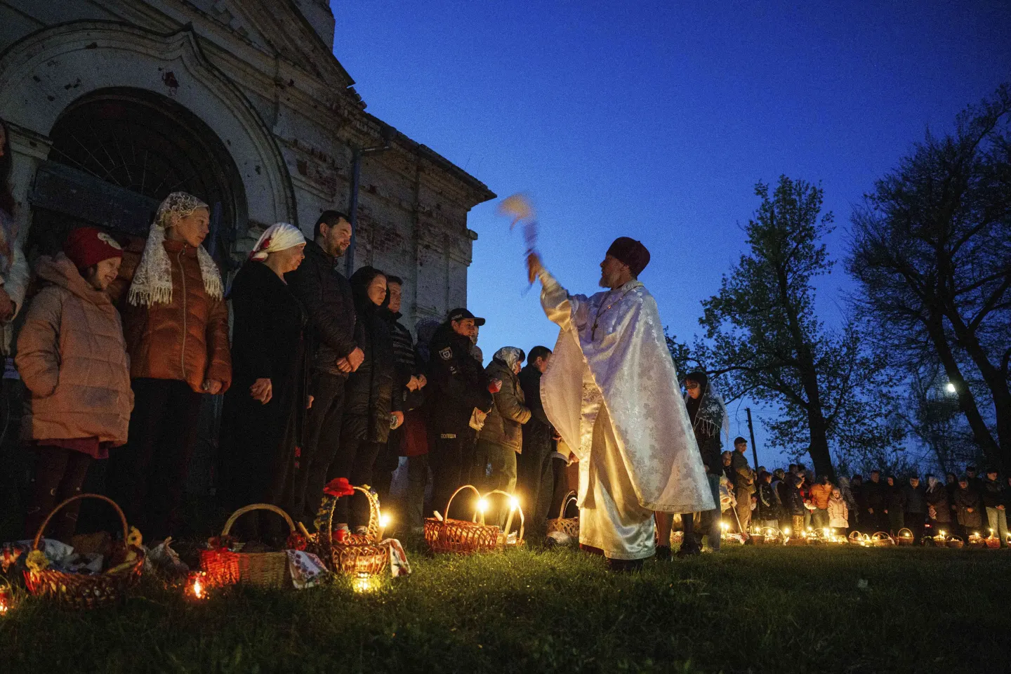 Священик Сергій Зезуль освячує великодні кошики перед церквою, зруйнованою внаслідок боїв між російсько-українськими військами, під час святкування православного Великодня в селі Лукашівка, Україна, у неділю, 20 квітня 2025 року.